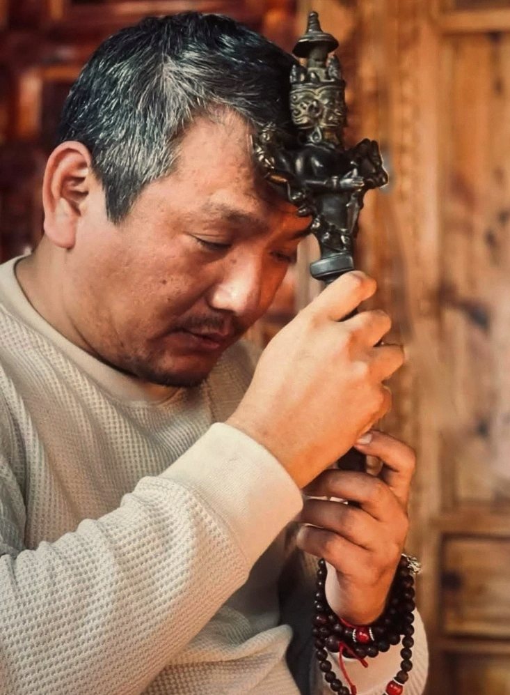 Rinpoche hành trì với phurba, mắt nhắm, tay lần chuỗi