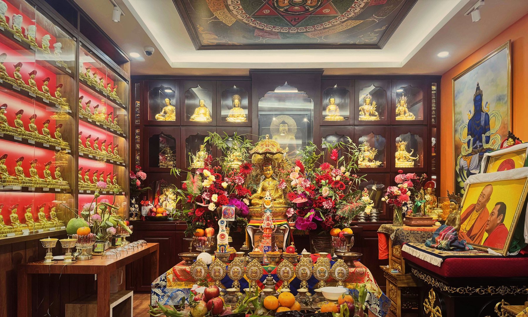 Phòng thờ chính trong ngày lễ: tủ tượng vàng nền đỏ, trần mandala, hoa cúng dường